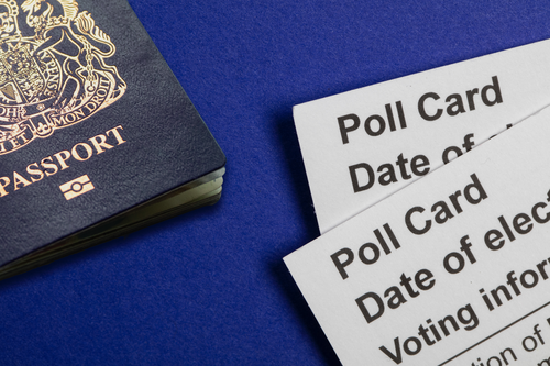 Polling cards and a blue UK passport on a blue background